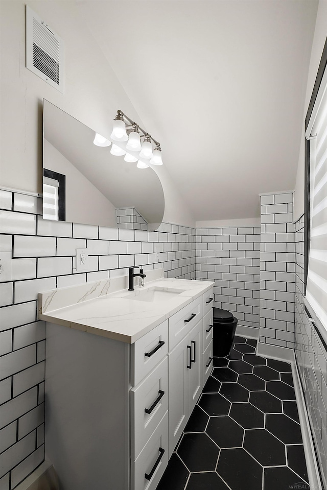 bathroom with visible vents, lofted ceiling, tile walls, and tile patterned floors