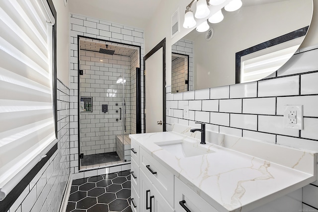 full bathroom featuring backsplash, tile patterned flooring, vanity, a shower stall, and tile walls