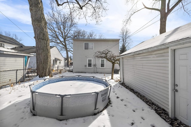 snow covered back of property with fence and an outdoor pool