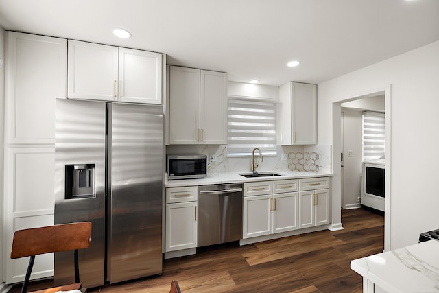 kitchen with a sink, white cabinetry, appliances with stainless steel finishes, decorative backsplash, and dark wood finished floors