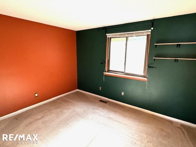 carpeted spare room featuring visible vents and baseboards