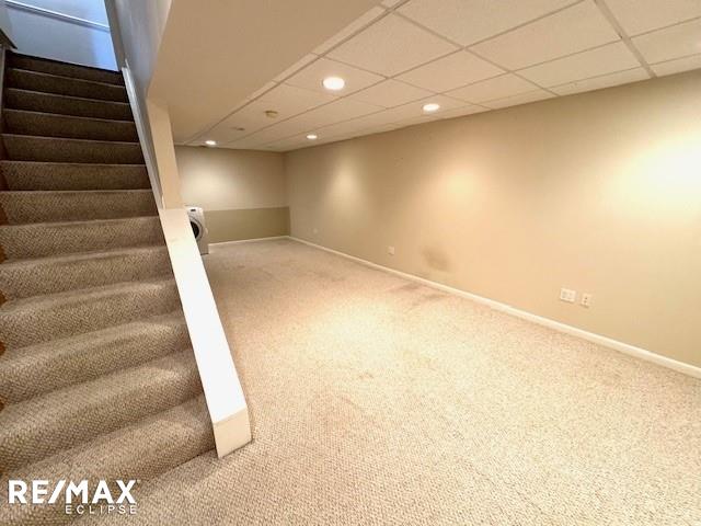 finished below grade area featuring carpet floors, a paneled ceiling, recessed lighting, baseboards, and stairs