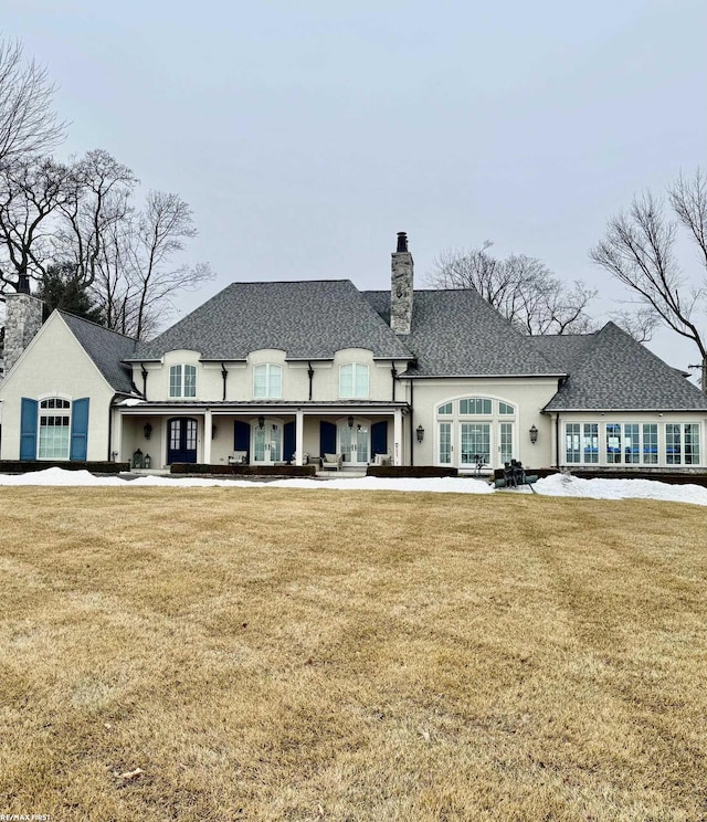 back of property featuring a chimney and a yard