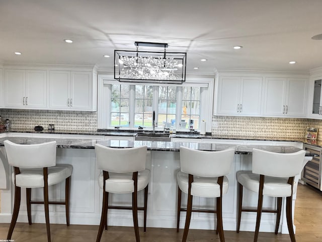 kitchen featuring wine cooler, white cabinets, backsplash, a center island, and light wood finished floors