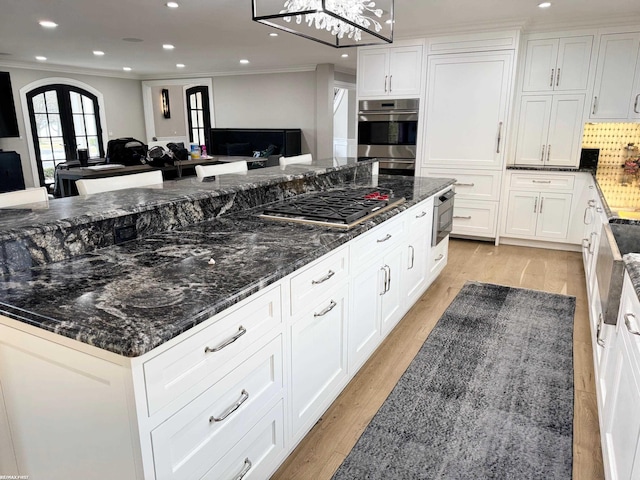 kitchen with french doors, appliances with stainless steel finishes, open floor plan, white cabinets, and light wood-type flooring