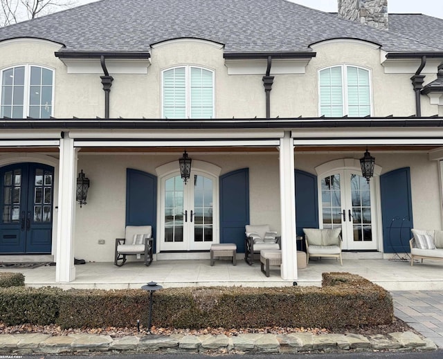 back of house featuring french doors, a shingled roof, and stucco siding