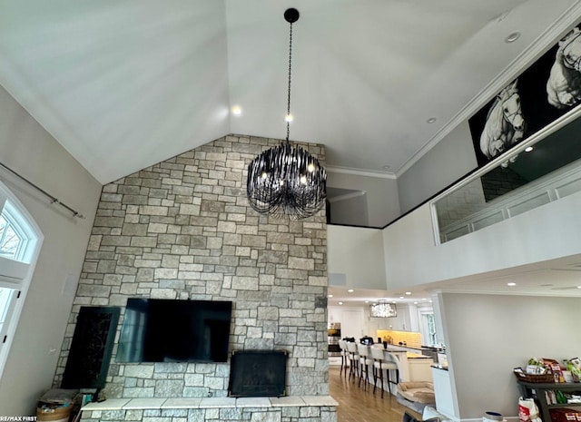 interior details with crown molding, a stone fireplace, a notable chandelier, and wood finished floors