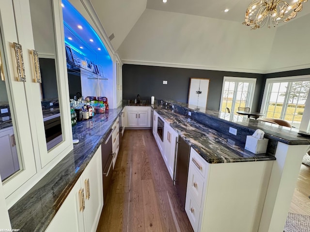 kitchen featuring high vaulted ceiling, dark wood-style flooring, a sink, white cabinets, and dark stone counters