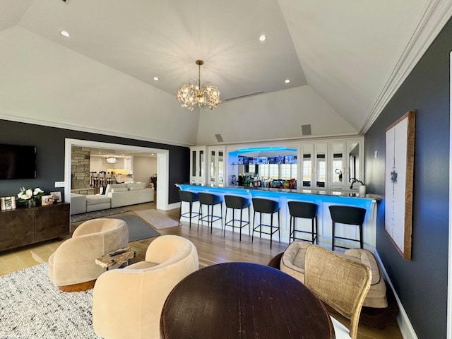 living area with a chandelier, high vaulted ceiling, baseboards, and wood finished floors