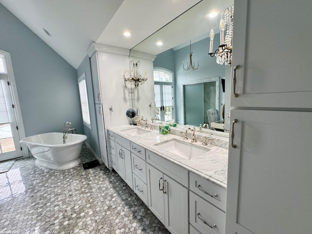 full bathroom featuring lofted ceiling, a freestanding tub, double vanity, and a sink