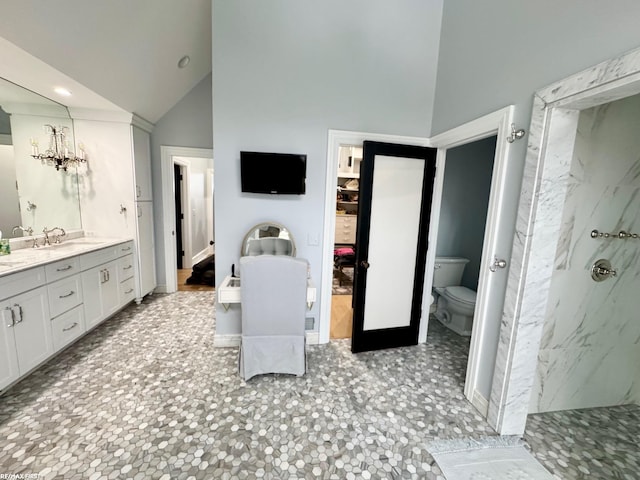 full bathroom with vanity, high vaulted ceiling, a marble finish shower, and toilet