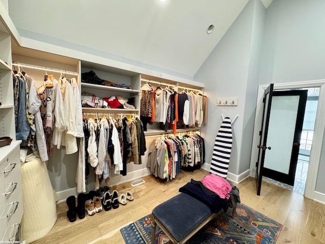 spacious closet with high vaulted ceiling and wood finished floors