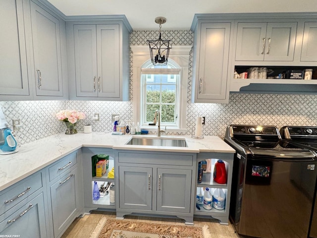 kitchen with open shelves, gray cabinets, a sink, light stone countertops, and independent washer and dryer