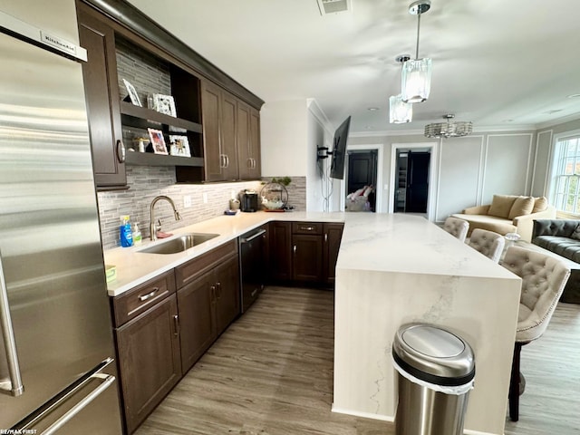 kitchen featuring built in fridge, open shelves, open floor plan, a sink, and dishwasher