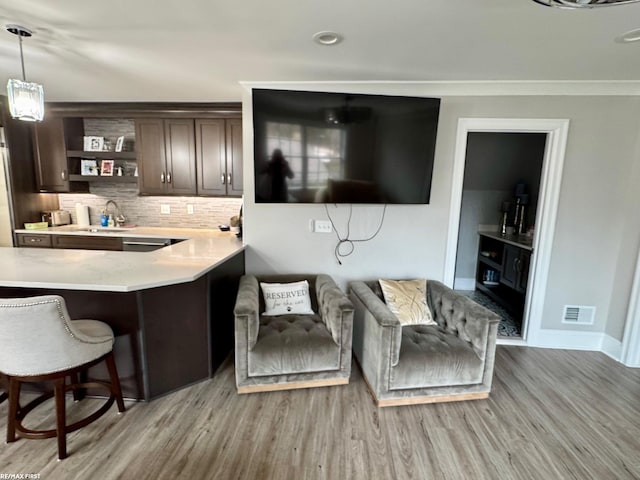 bar featuring tasteful backsplash, baseboards, visible vents, light wood-type flooring, and a sink