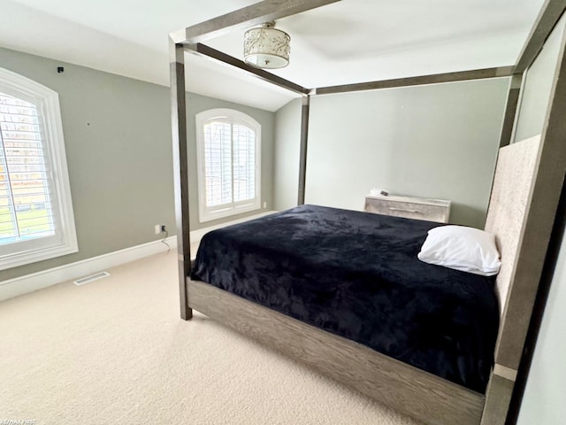 carpeted bedroom with lofted ceiling, multiple windows, visible vents, and baseboards