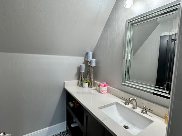 bathroom featuring lofted ceiling, vanity, and baseboards