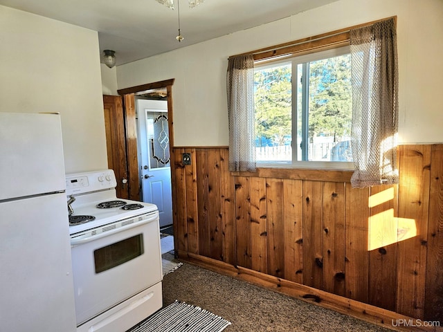 kitchen featuring white appliances, wood walls, and wainscoting