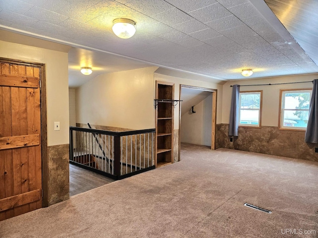 interior space featuring carpet, visible vents, and a textured ceiling