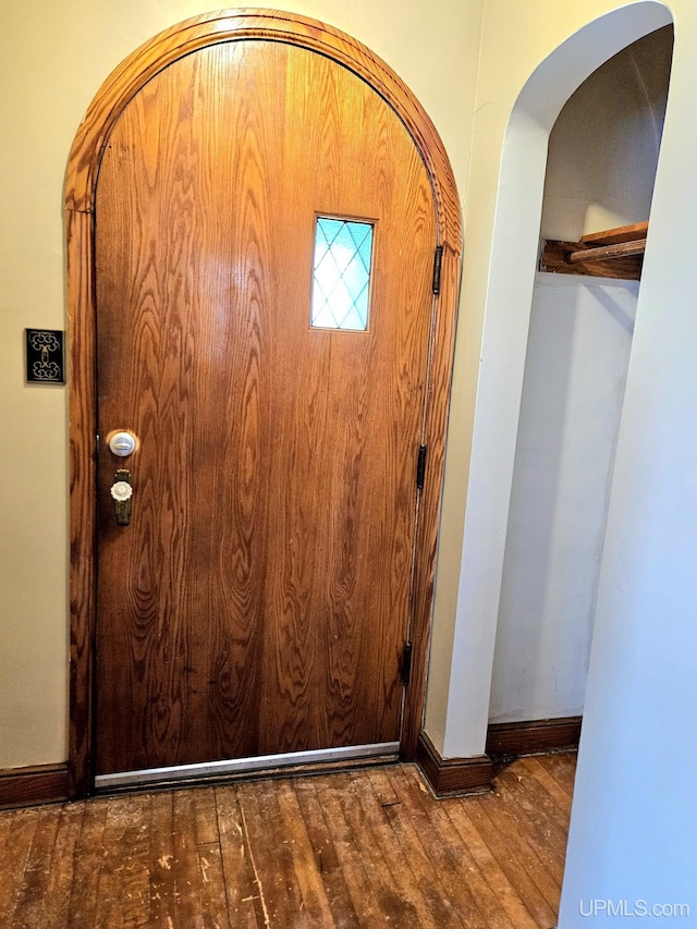 interior space with arched walkways, baseboards, and hardwood / wood-style floors