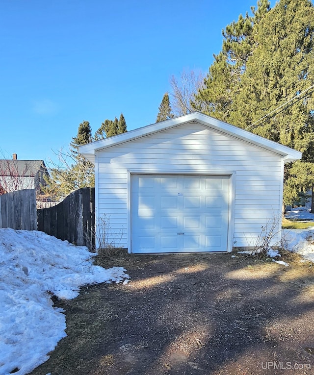 detached garage featuring fence and dirt driveway