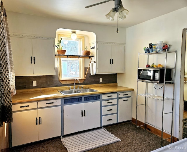 kitchen featuring a sink, a ceiling fan, white cabinets, tasteful backsplash, and stainless steel microwave