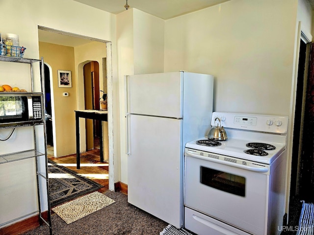 kitchen featuring white appliances, carpet, and arched walkways