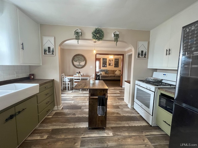 kitchen with arched walkways, white gas range, dark wood finished floors, and freestanding refrigerator