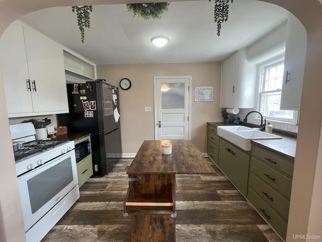 kitchen with arched walkways, dark wood-type flooring, black appliances, white cabinetry, and a sink