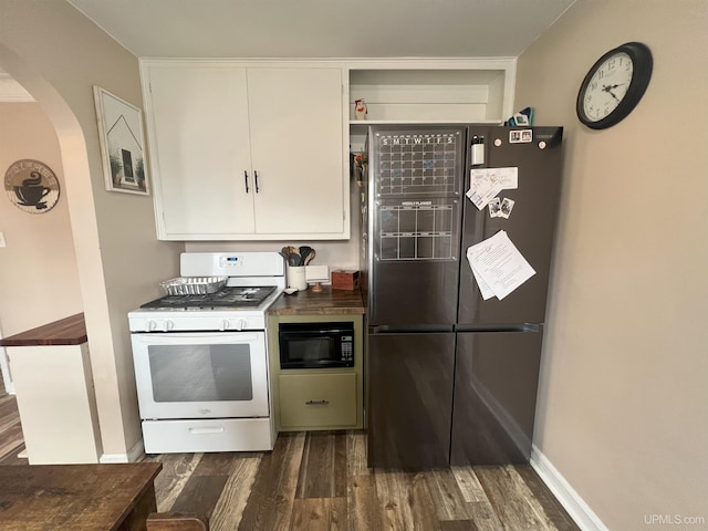 kitchen with white range with gas cooktop, arched walkways, dark wood-type flooring, freestanding refrigerator, and black microwave