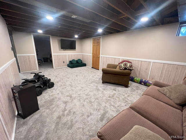 living area with carpet, wainscoting, and wooden walls