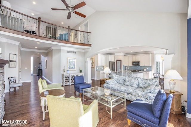 living area featuring arched walkways, high vaulted ceiling, visible vents, baseboards, and dark wood-style floors