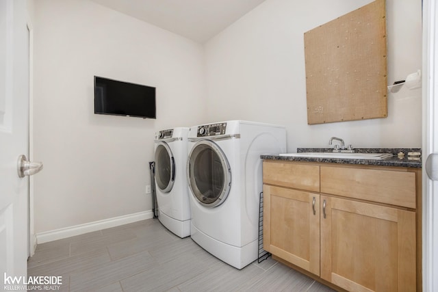 laundry room featuring cabinet space, a sink, washer and clothes dryer, and baseboards