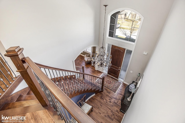 entryway featuring a notable chandelier, a high ceiling, wood finished floors, and stairs