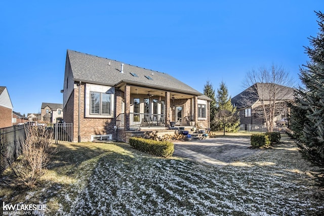 rear view of property with fence, a ceiling fan, and brick siding