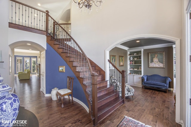 stairway with a towering ceiling, baseboards, hardwood / wood-style floors, and built in features