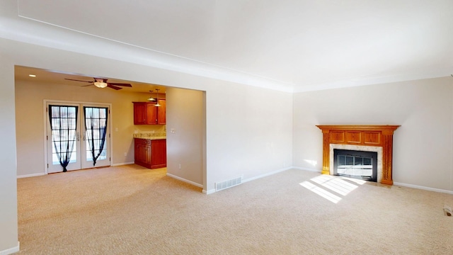 unfurnished living room featuring a fireplace with flush hearth, visible vents, baseboards, and light colored carpet