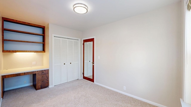 unfurnished bedroom with baseboards, built in study area, and carpet flooring