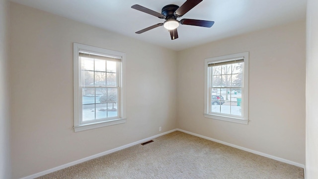 spare room featuring visible vents, ceiling fan, light carpet, and baseboards