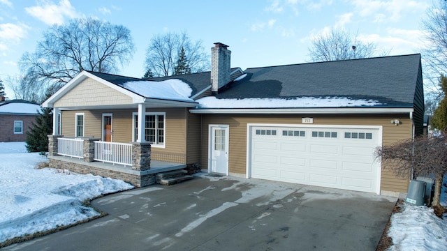 view of front of property featuring a porch, driveway, a chimney, and a garage