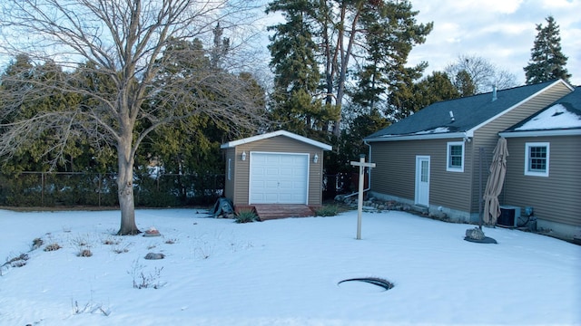 yard layered in snow with an outbuilding, central air condition unit, entry steps, fence, and a garage