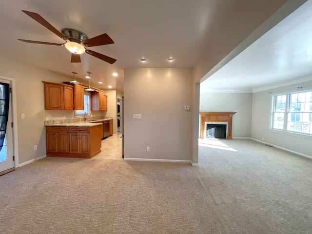 kitchen featuring brown cabinets, open floor plan, light carpet, a tile fireplace, and baseboards