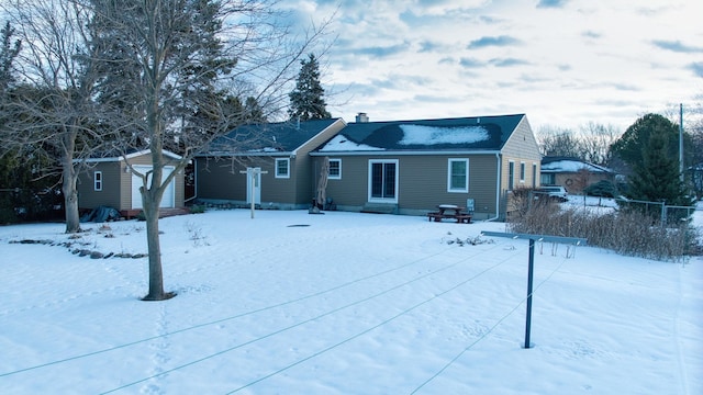 snow covered house featuring an outbuilding, a storage shed, a chimney, and entry steps