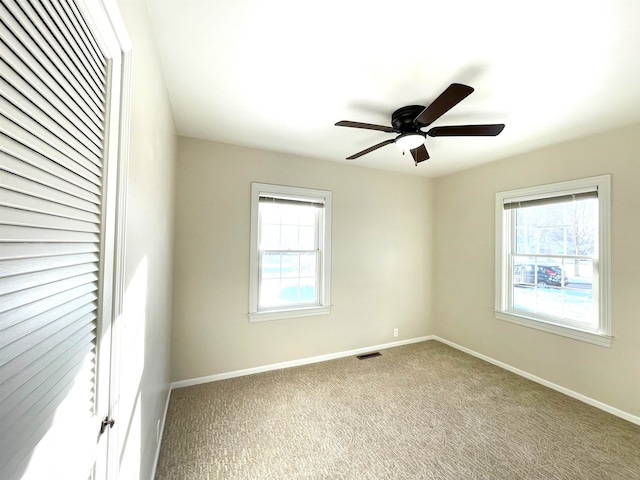 unfurnished room with carpet floors, plenty of natural light, and baseboards