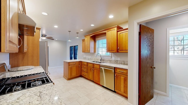 kitchen featuring recessed lighting, appliances with stainless steel finishes, a sink, light stone countertops, and baseboards