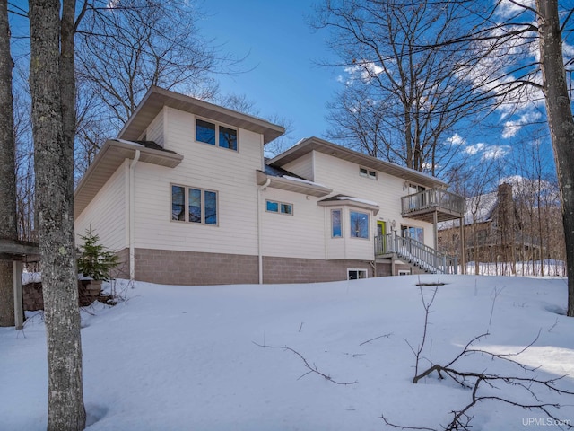 snow covered rear of property with a balcony