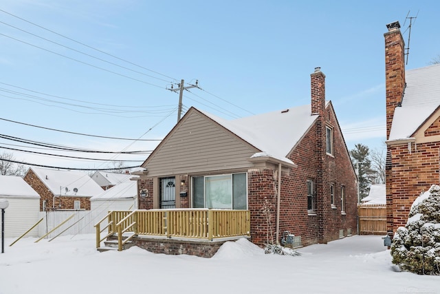 view of front of house with brick siding, fence, and a chimney