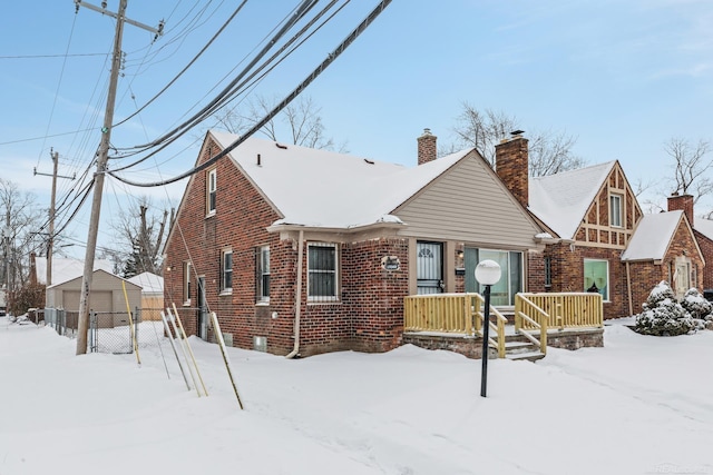 view of front of house with a garage, an outbuilding, brick siding, and a chimney