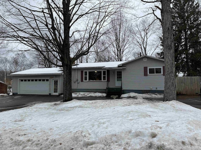 ranch-style house featuring a garage, driveway, and fence