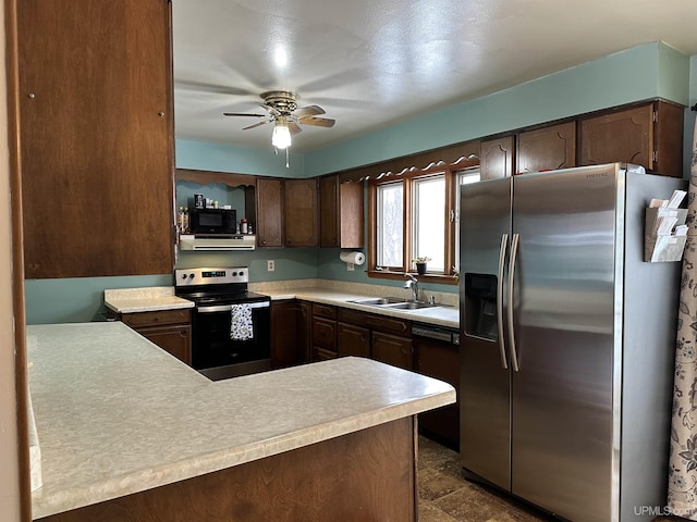 kitchen with ceiling fan, a peninsula, a sink, light countertops, and black appliances